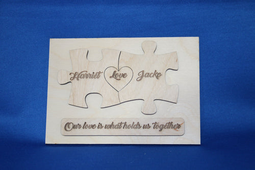 Personalized wooden puzzle plaque with engraved names, heart, and message assembled on blue background