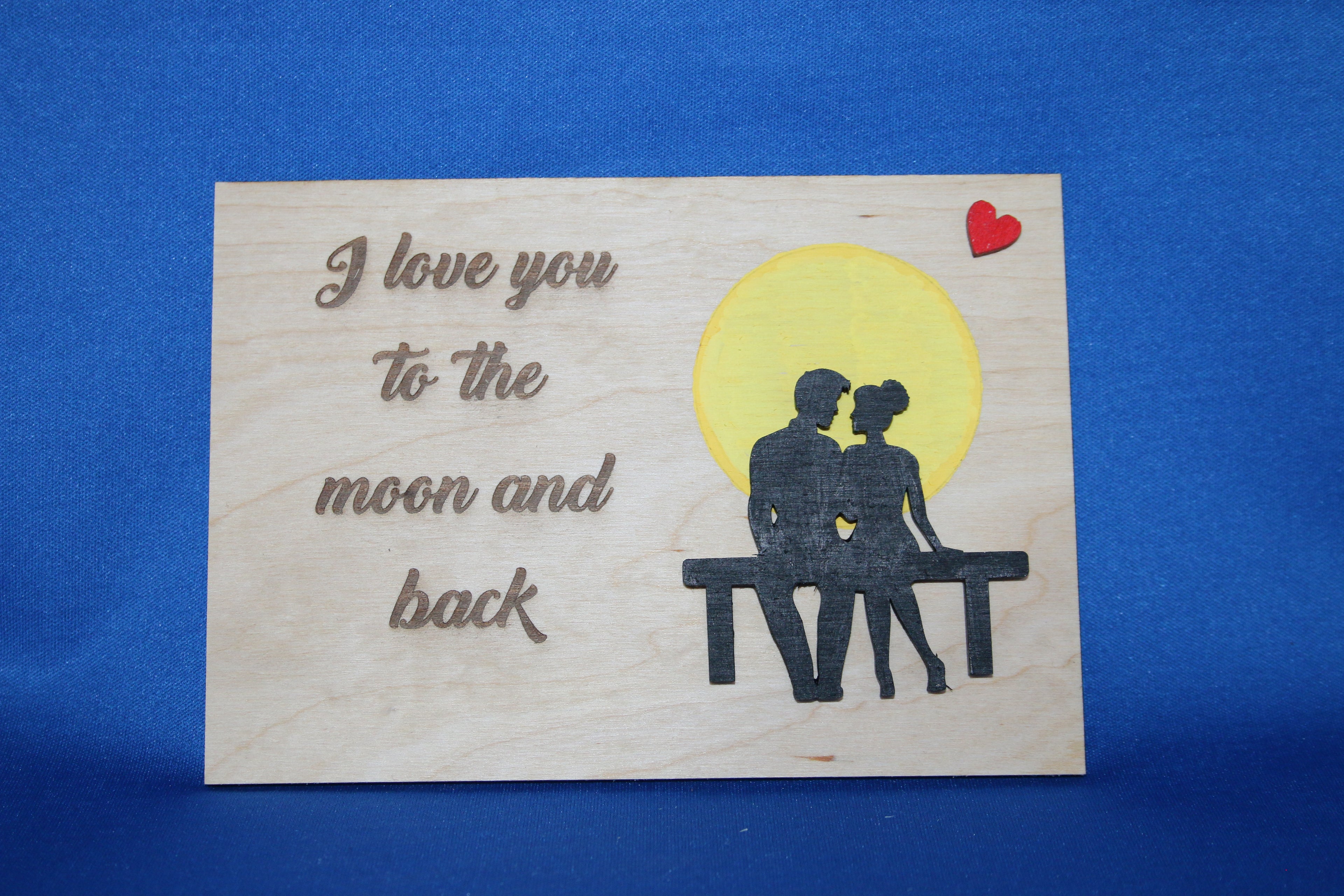 Wooden plaque with romantic couple, yellow moon, red heart, and engraved text 'I love you to the moon and back'