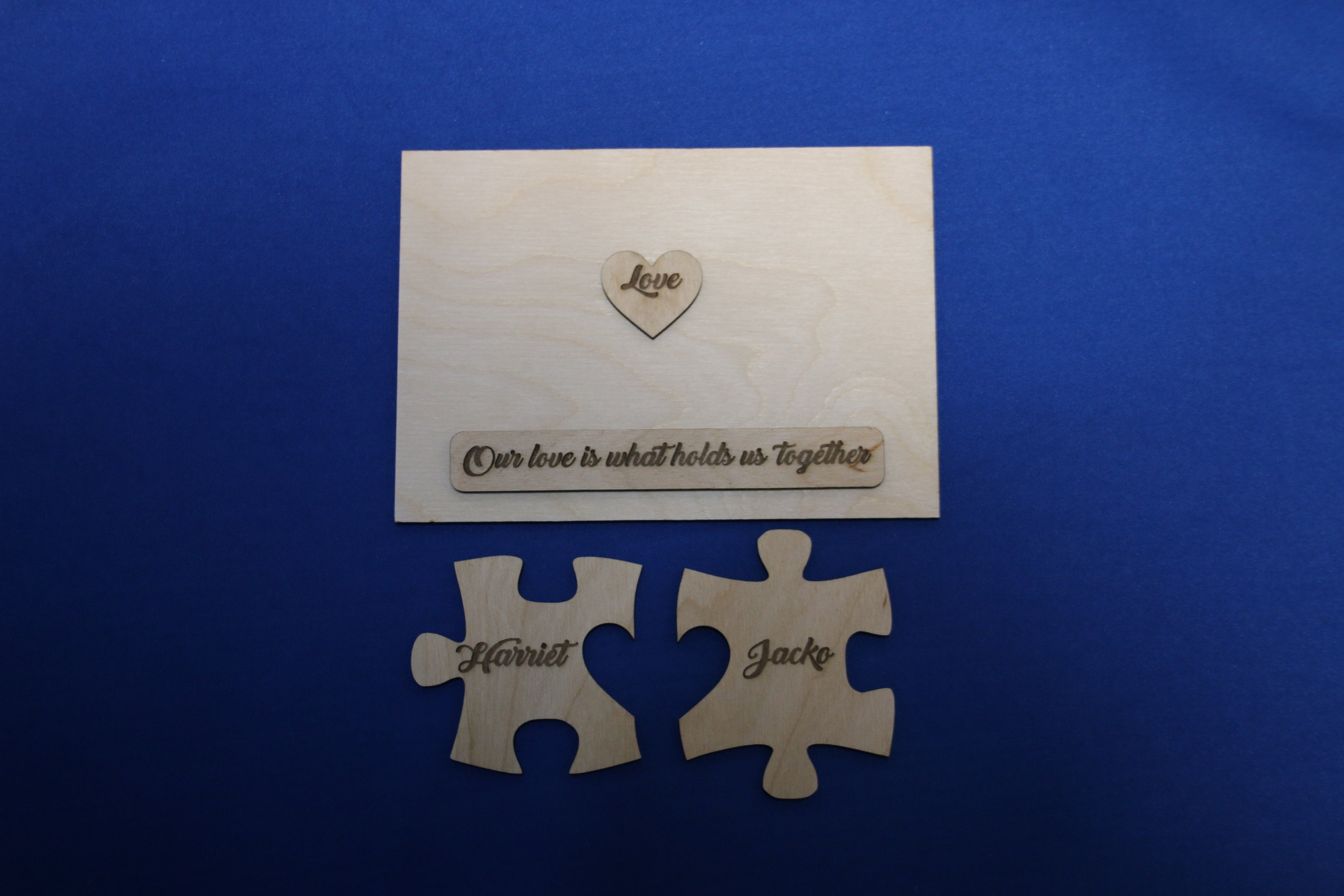 Disassembled personalized wooden puzzle plaque showing name pieces, heart, and engraved message